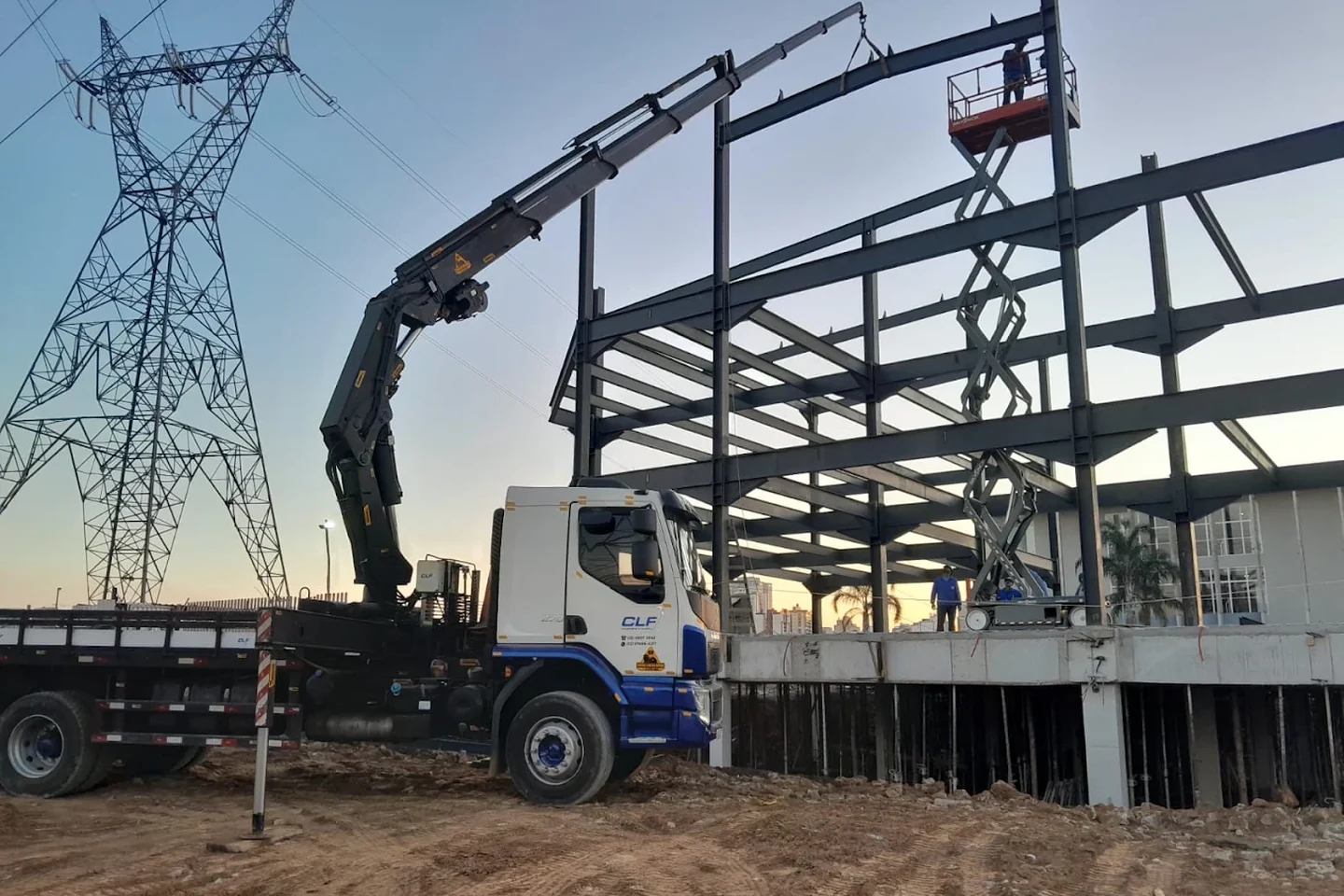Caminhão munck da CLF operando em canteiro de obras no fim da tarde