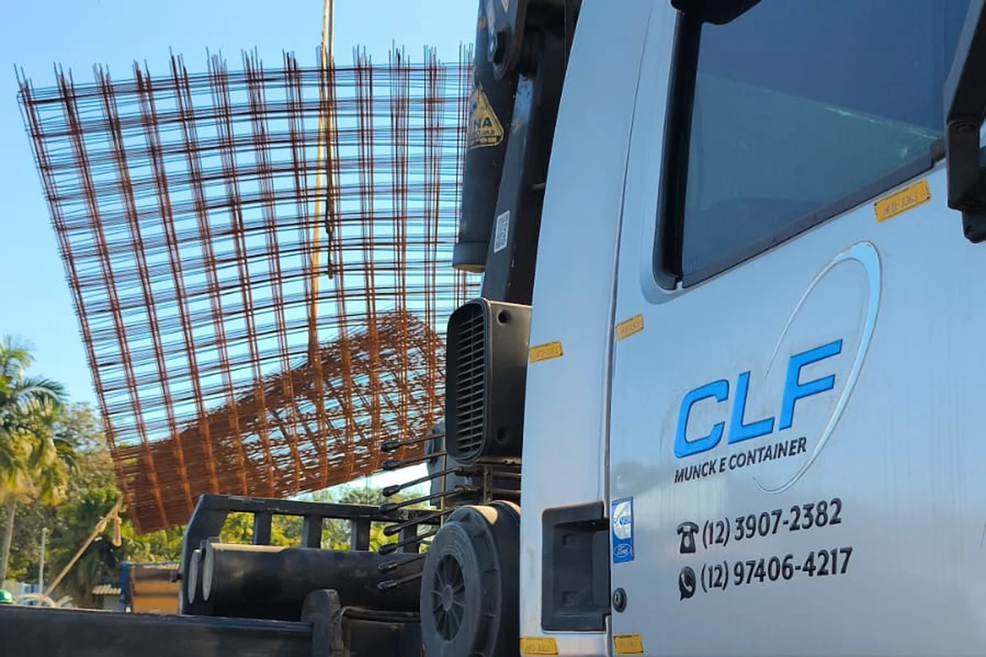 Caminhão munck da CLF içando uma malha de armação de ferro em obra